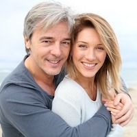 Cheerful mature couple embracing by the beach